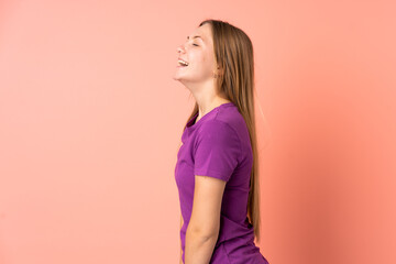 Obraz premium Teenager Ukrainian girl isolated on pink background laughing in lateral position