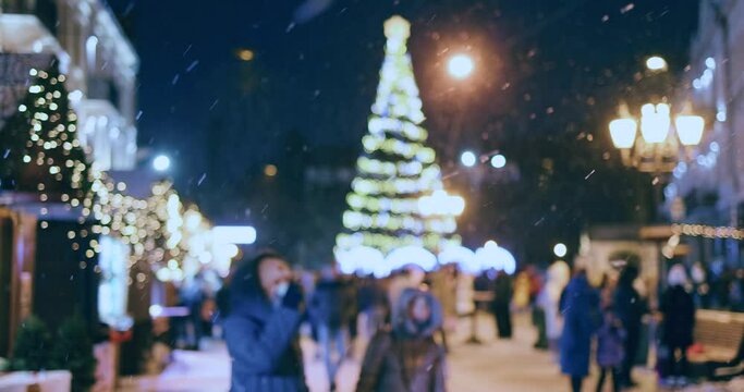 defocused crowded christmas fair at the city square in beautiful snowy night