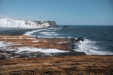 Dramatic winter landscape of Icelandic Black Sand Beach Reynisfjara near town Vik. Stormy sea shore of volcanic black beach in fog weather