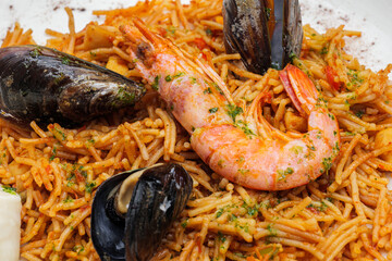 Noodles with tomato sauce and seafood, mussels and shrimps on white plate.