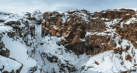 Secret canyon named Mulagljufur canyon in South Iceland. Waterfall below mountain top in winter and...