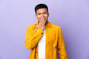 Young Ecuadorian man isolated on purple background happy and smiling covering mouth with hand