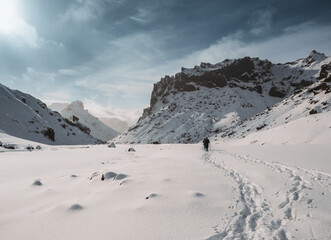 Two friends hiking in and winter iceland nature in highlands through snow covered mountains on a beautiful day with blue sky and sun.