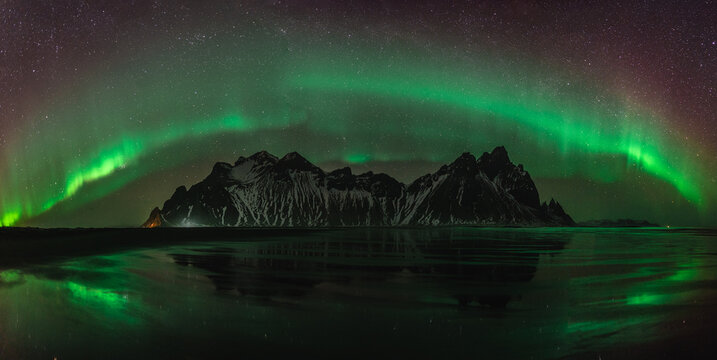 Vestrahorn Stockknes mountain range with aurora borealis and reflection at the beach in Iceland. One of the most beautiful famous nature heritage in Iceland.