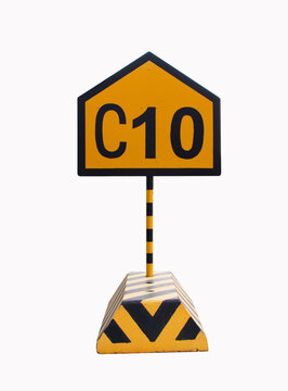Road traffic signs yellow black C10 (Charlie) isolated on white background. Aluminum signs with concrete bases indicating traffic signs. Used to give directions in the container yard in the port.