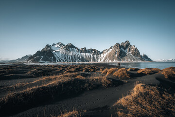 Young man tourist standing at beach during sunset runrise and gorgeous reflection of Vestrahorn...
