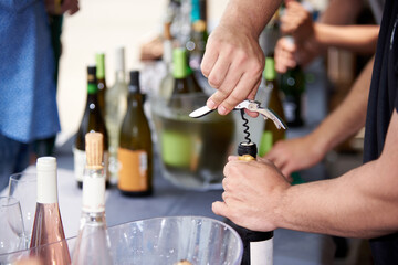 Unrecognizable man uncorking a bottle of wine with corkscrew