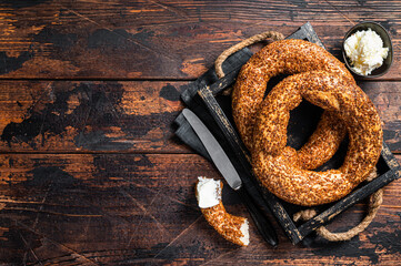 Stack of fresh baked Turkish simit bagel with kaymak. Wooden background. Top view. Copy space