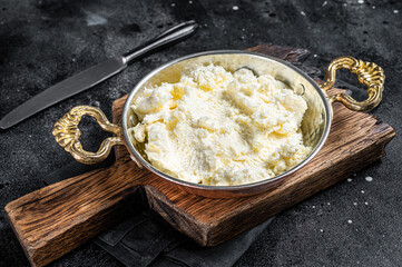 Kaymak Clotted cream, butter cream in a rustic pan. Black background. Top view