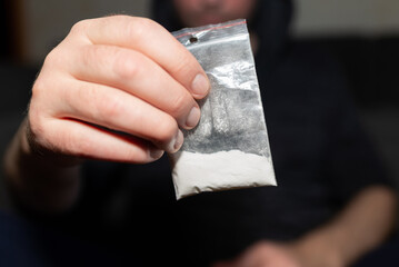 Criminal holding plastic bag with drug.Man holding transparent plastic zip lock bag with drugs. Concept-criminal with drugs.closeup,selective focus,toned.