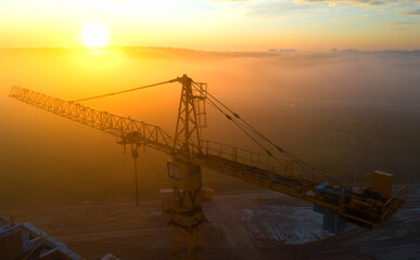 Construction cranes at dawn in the morning mist.
