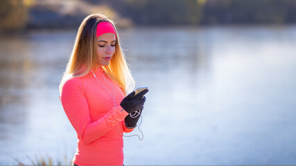 Young sporty woman checking her fitness tracker on smartphone during morning running.