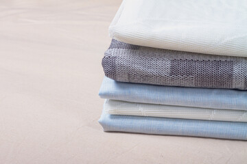 A stack of neatly folded white, blue, gray fabric