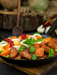 Stew with meat and vegetables in black iron dish. Traditional gourmet goulash in a rustic kitchen