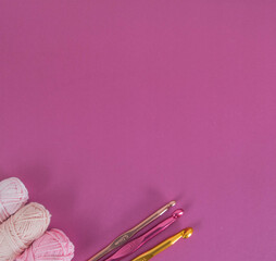 colorful wool balls on pink ground with crochet hooks