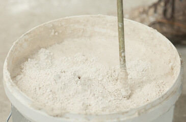 the process of mixing plaster mortar putty mixer in a bucket close-up.