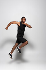 Fototapeta na wymiar full length of fast african american sportsman levitating while running on grey.
