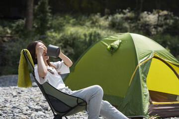 Woman camping  on a riverbank