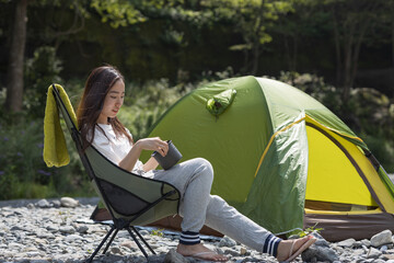 Woman camping  on a riverbank