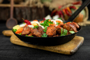 Stew with meat and vegetables in black iron dish. Traditional gourmet goulash in a rustic kitchen