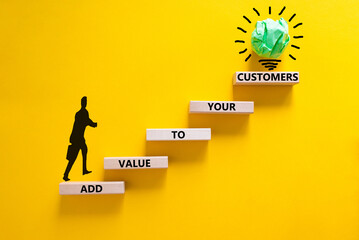 Add value to your customers symbol. Concept words 'Add value to your customers' on wooden blocks on a yellow background, copy space. Businessman icon, light bulb. Business, customers value concept. - obrazy, fototapety, plakaty
