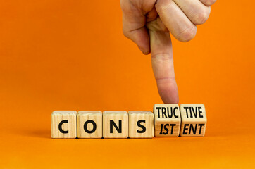 Constructive or consistent symbol. Businessman turns cubes, changes the word consistent to constructive. Beautiful orange background, copy space. Business, constructive or consistent concept. - obrazy, fototapety, plakaty