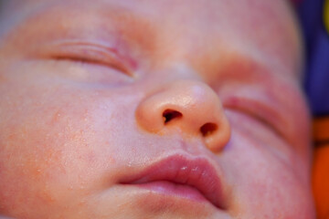 Fototapeta premium the face of a sleeping newborn caucasian baby. Focus to mouth lips. High quality photo. close up view macro closeup