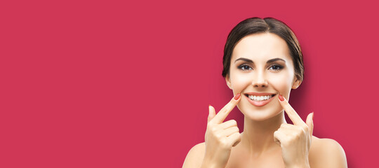 Happy excited woman pointing toothy smile. Face portrait of optimistic girl, over red color background with copy space, for some advertising sign text or slogan. Optimism or Dental Health Care concept