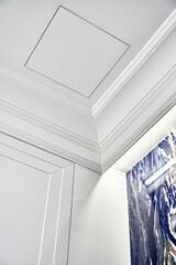 Part of elegant ceiling with LED backlight behind crown molding and small inspection hatch over...