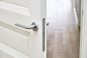 Stylish white inner open door with silver handle to room with elegant oak parquet flooring as...