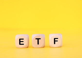 wooden cube with ETF text on yellow background