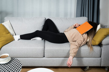 Young college student woman fell asleep on the sofa after long hard study for final exam. Female...