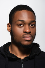 Obraz premium african american man in hoodie looking at camera isolated on grey.