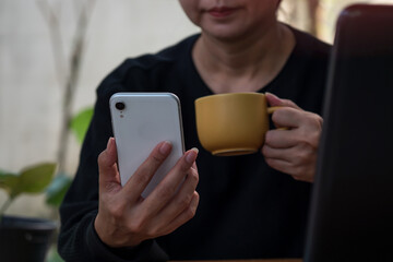 The businesswoman is drinking coffee in the yard while on the phone. Internet concept and business, as well as investment