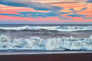 Fototapeta na wymiar Evening restless sea. High waves on the evening beach, the rays of the setting sun.