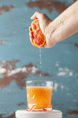 Woman hand pour citrus juice from red orange or grapefruit into glass