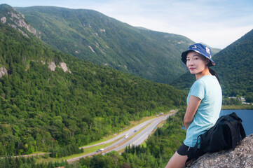 chinese woman leaning on a large boulder in new hampshire above franconia notch