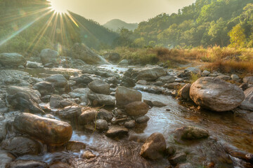 Beautiful Reshi River water flowing on rocks at dawn, Sikkim, India - sun rays at the background...