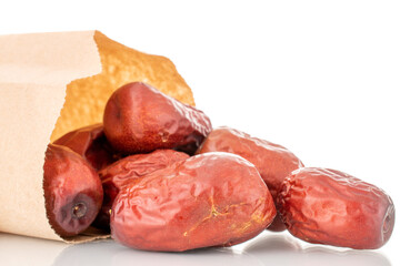 Several dried ziziphus berries with a paper bag, close-up, isolated on white.