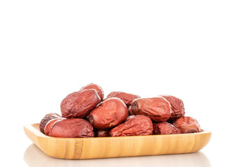 Several slice dried ziziphus berries on a wooden tray, close-up, isolated on white.