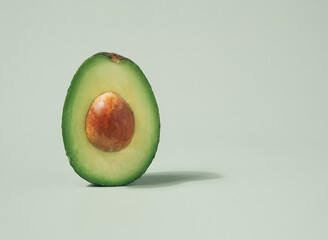 Avocado half macro shot isolated on a pastel green background. Fresh ingredients minimal concept.