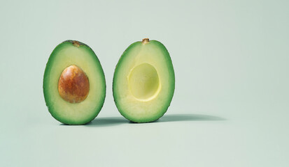 Avocado halves close up on a light green background. Vegan diet minimal concept.