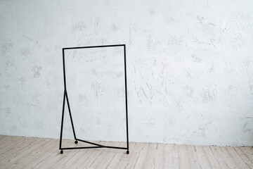 Metal hanger floor on a minimalist background. Rack for clothes on wheels. Light walls, wooden floor in the room.
