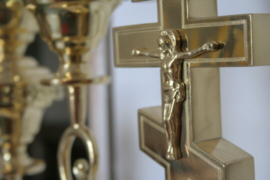 Close-up of a gilded cross with a crucifix against the background of a candlestick