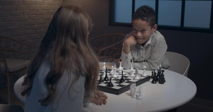 Little children playing chess at home in evening