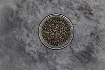 An open glass jar of sturgeon caviar. Top view.