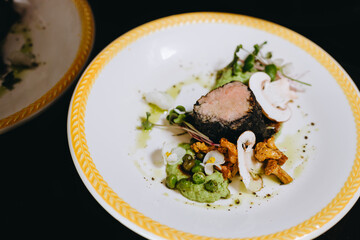 There is a silver plate of the dish that includes fried meat, a few pieces of mushrooms, some green.