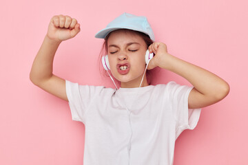 cute girl headphones in a white t-shirt and a cap pink background