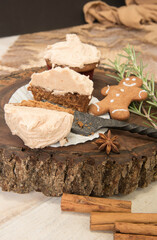 Gingerbread cupcake halved sitting on a wood slice. Gingerbread man, cinnamon sticks, star anise, rosemary sprigs.