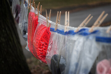 Bags of Winter Gloves, Hats, Scarves, and Socks hand on a clothesline for the needy.  New winter wear is hung outside the United Methodist Church of Windsor in Upstate NY for the needy this winter.